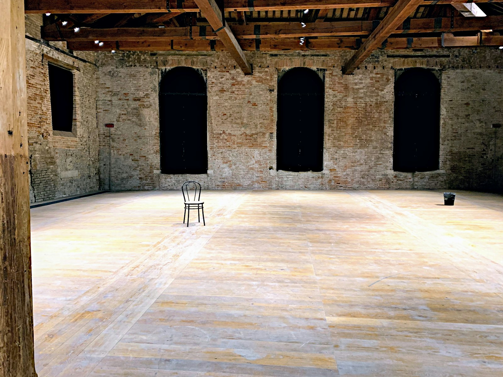 A bare, empty rehearsal room with a single chair in the middle