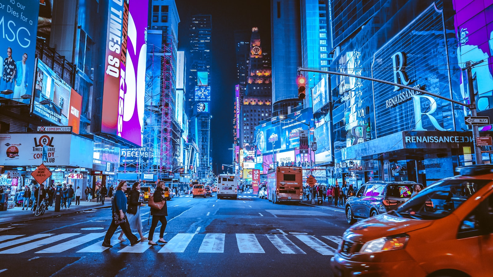 A New York City street at night with neon signs and lights